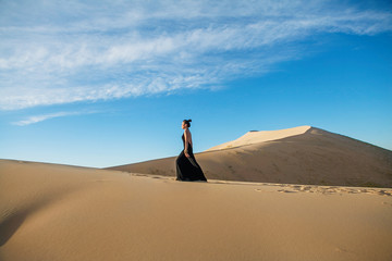 Fashion asian woman model posing in a black long dress in desert