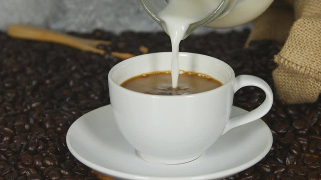 4k of Pouring milk into a cup of coffee