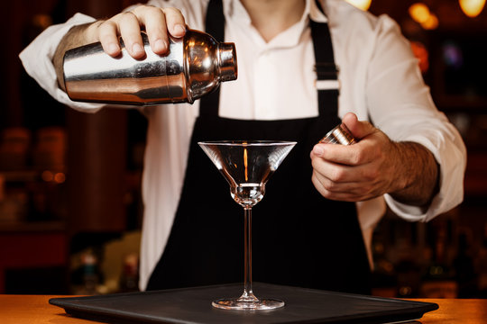 Barman in making cocktail at a nightclub. Nightlife concept. No face. Pouring into glass