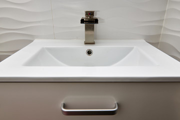 Fototapeta premium White modern design bathroom vanity with white marble sink and brushed nickel waterfall faucet