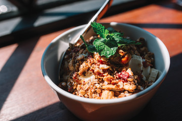 The bowl with smoothie, muesli, fruits and berries on the wooden table