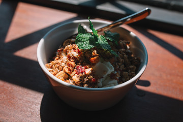 The bowl with smoothie, muesli, fruits and berries on the wooden table