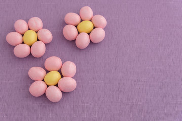 Candy coated Easter eggs in a flower pattern on a purple background
