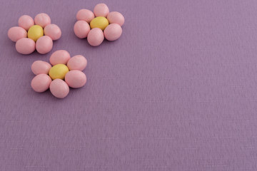 Obraz na płótnie Canvas Candy coated Easter eggs in a flower pattern on a purple background 