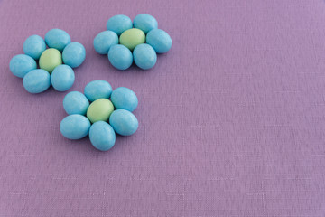 Candy coated Easter eggs in a flower pattern on a purple background
