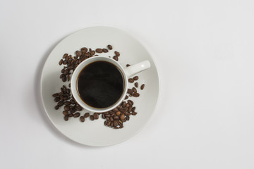 Above view of coffee cup on saucer with coffee beans
