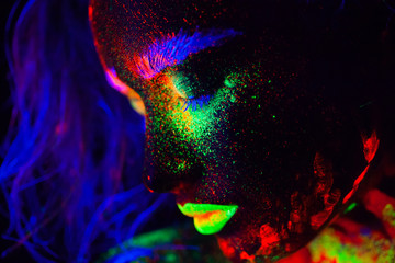 Beautiful extraterrestrial model woman with blue heair and green lips in neon light. It is portrait of beautiful model with fluorescent make-up, Art design of female posing in UV with colorful make up