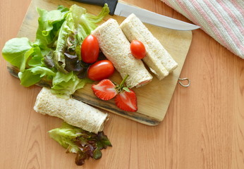 bread roll and salad on wooden chopping block