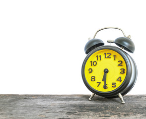 Closeup black and yellow alarm clock for decorate show half past six or 6:30 a.m. on old brown wood desk isolated on white background with copy space