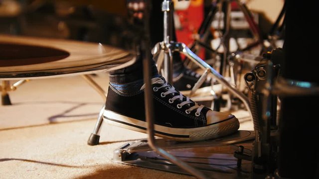 Drummer's foot in sneakers moving drum bass pedal