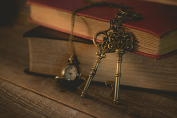 close-up old key and pocket watch with stack of book on night light in vintage tone, waiting,...