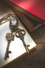 Pocket watch and Old vintage key on  stack of old book with copy space in morning light for time, unlock or eductaion concept