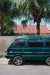 Minivan on the asian street under the palm tree
