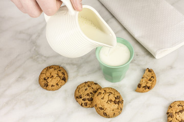 Milk poured into glass, with chocolate chips cookies