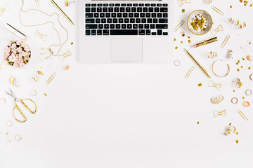 Beauty blog background. Workspace with laptop, gold style feminine accessories. Golden tinsel, scissors, pen, rings, necklace, bracelet on white background. Flat lay, top view office table desk.