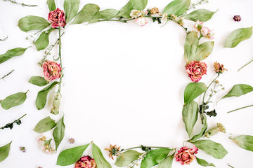 Round frame wreath pattern with roses, pink flower buds, branches and leaves on white background. Flat lay, top view. Flowers pattern