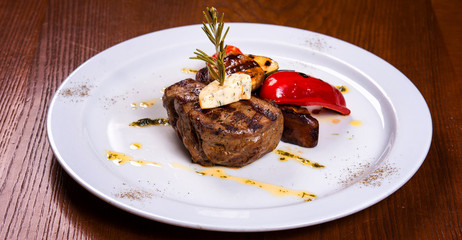 fat steak with rosemary and fried vegetables cheese on white plate