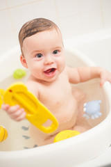 baby boy bathes with toys