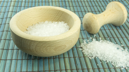 Sea salt in a wooden mortar on a wood background