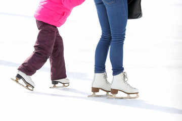Fototapeta na wymiar child and adult skates at the ice rink.