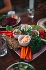 The plate full of vegetables, sauces and bread on the wooden table