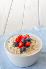Bircher Muesli with Fresh Strawberries and Blueberries on Top with Copy Space Vertical