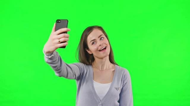 Young Woman Taking Selfie and pulling faces for the photo on Green Screen Background