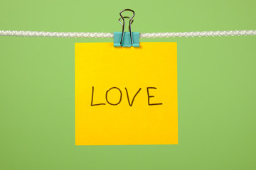 Yellow paper note on clothesline with text Love