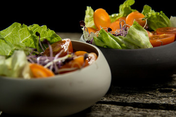 Preparing salad with radish sprouts, carott, green salad, tomato served on  an old wooden table