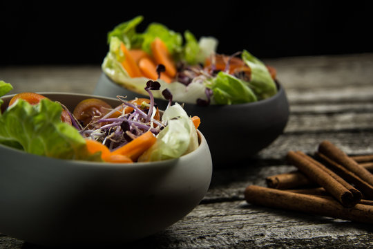 Preparing salad with radish sprouts, carott, green salad, tomato served on  an old wooden table