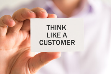 Businessman holding a card with THINK LIKE A CUSTOMER message
