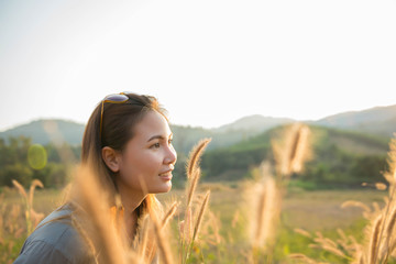 Woman standing in the midst of a beautiful natural grass happily.