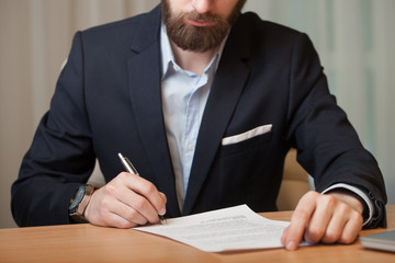 Businessman in office signs the document