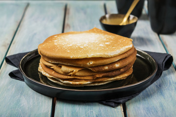Pile of hot homemade yeast pancakes on a wooden background. Family breakfast. Close-up. Selective focus 