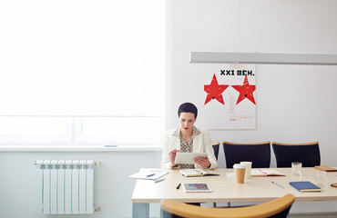 Contemporary businesswoman preparing for important meeting sitting alone at table in conference...