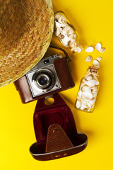 Summer or vacation concept. Straw hat with old vintage camera and shells on vibrant background. Top view.