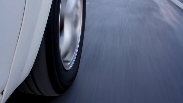 Rolling rubber tire of white car on the asphalt road. Close up of driving. Car mounted camera, on tire. 