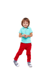 Full body portrait of shy little boy dressed in bright colorful clothes standing giggling and  posing awkwardly against white background