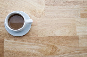 white cup of coffee on wooden table and copy space, soft focus