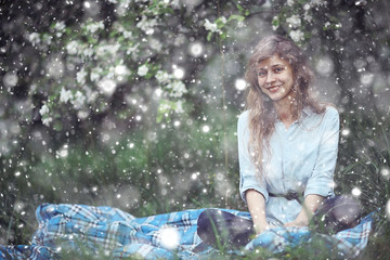 Fototapeta na wymiar adult girl is sitting in a blossoming apple orchard Spring