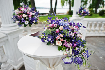 Decoration of wedding arch with registration table for newlyweds with violet and purple flowers.