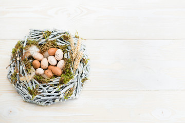 Easter eggs in nest over wooden background. View with copy space