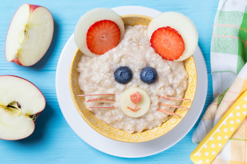 Funny oat porridge with mouse face made of fruits and berries, food for kids idea, top view