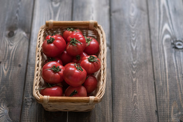 a basket of ripe tomatoes on a wooden background