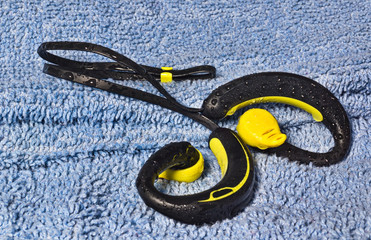 Waterproof earphones, yellow and black, beaded with water.
