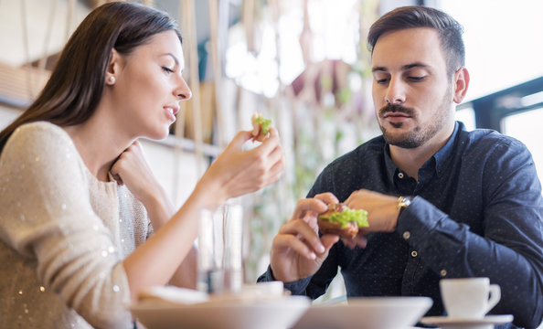 Beautiful young couple sitting in a cafe, having breakfast. Love, food, lifestyle