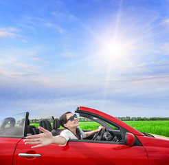 Woman in a red carin a field with wind power.