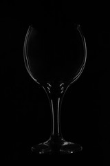 Glass bokal on a black background. Silhouette of glass reflects light, promotional photo. Laconic minimalism, creative photo glass glass. Abstraction, outlines of glass