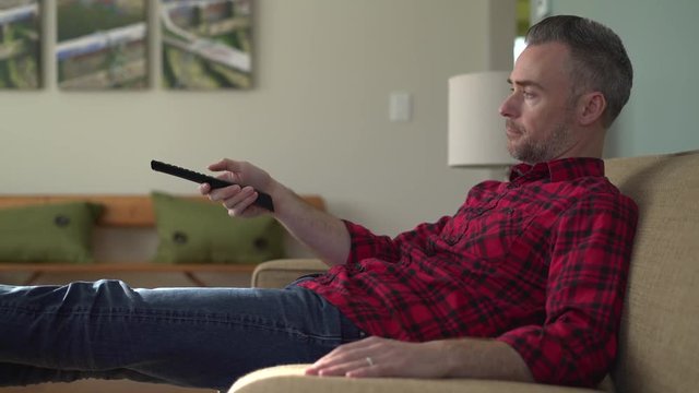 Lounging man tring to find a show to watch