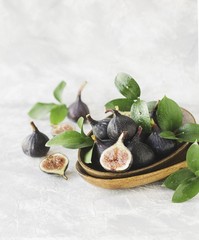 dark blue Fresh figs in a wooden bowl on a white marble table, selective focus